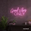 Baby pink neon sign that says Good Vibes Only against a dark wall.