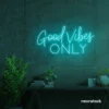 Good Vibes Only neon sign glowing in mint green on a textured wall.