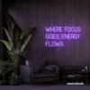 Where Focus Goes Energy Flows neon sign in purple for productivity decor and creative inspiration.