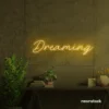 Dreaming neon sign in golden yellow for dreamy decor, teen bedrooms, and relaxing nooks.