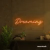 Dreaming neon sign in orange for dreamy decor, teen bedrooms, and relaxing nooks.