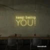 Keep Being You neon sign in warm white for empowerment decor, teen rooms, and creative wall spaces.
