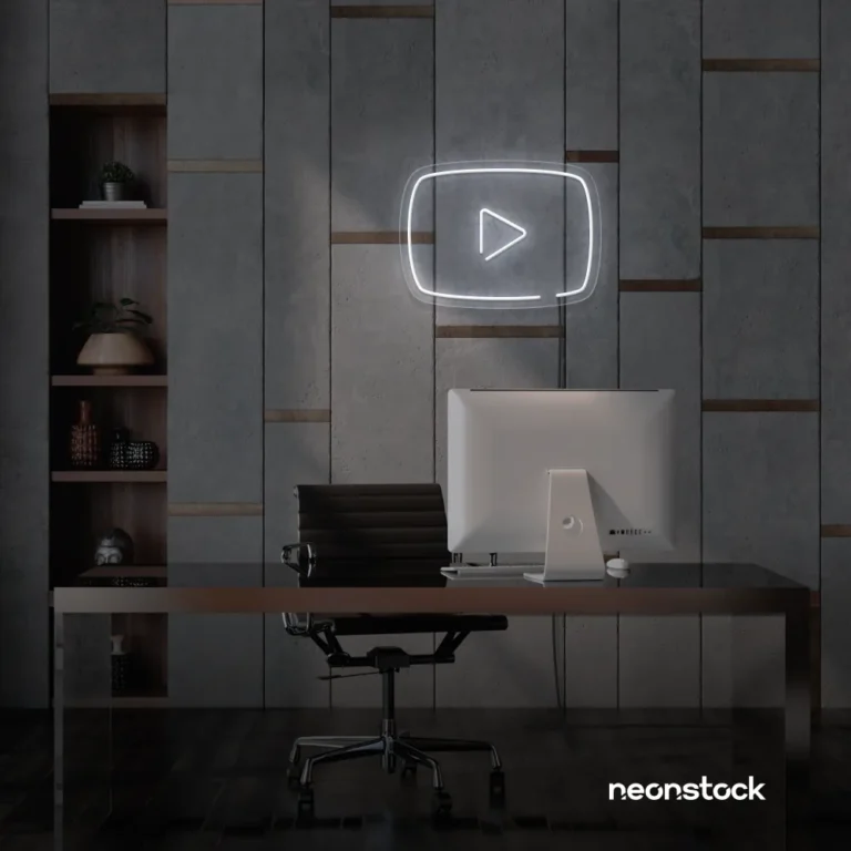 White play button neon sign on gray office wall above a modern desk