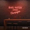 Save Water Drink Champagne neon sign in peachy pink for party kitchens, wine bars, and bubbly wall decor.