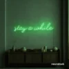 Stay Awhile neon sign in green for cozy cafes, home decor, and hospitality settings.