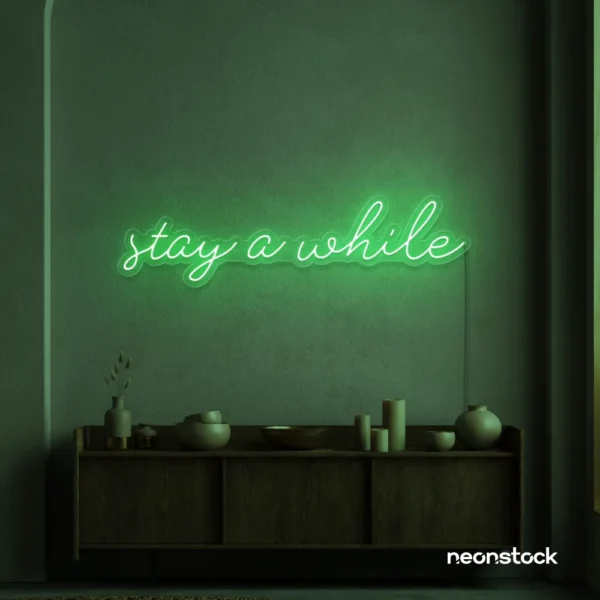 Stay Awhile neon sign in green for cozy cafes, home decor, and hospitality settings.