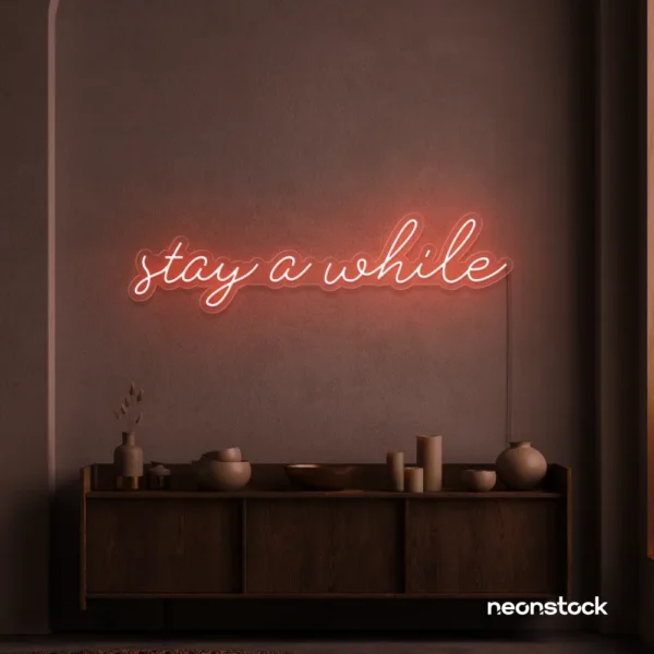 Stay Awhile neon sign in peachy pink for cozy cafes, home decor, and hospitality settings.