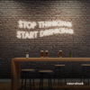 Stop Thinking Start Drinking neon sign in neutral white for bar walls, man caves, and party spaces.