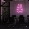 This Must Be The Place neon sign in baby pink for cozy salons, boutique shops, and cafe decor.