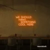 Neon sign text 'We should hang something cool here' in orange for wall art and home decor
