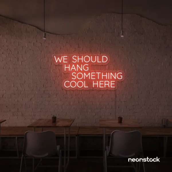 Neon sign text 'We should hang something cool here' in peachy pink for wall art and home decor