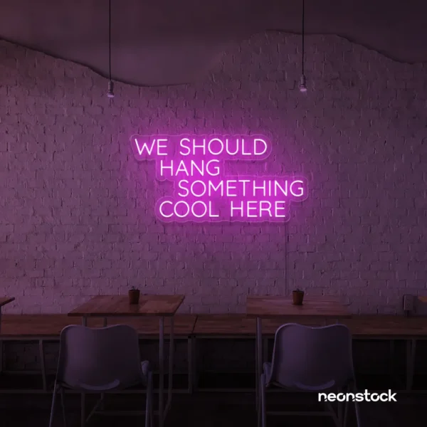 Neon sign text 'We should hang something cool here' in pink for wall art and home decor