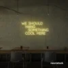 Neon sign text 'We should hang something cool here' in warm white for wall art and home decor